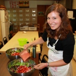 Our Marketing Assistant Rosalind pouring strawberry balsamic vinaigrette over strawberry greens salad